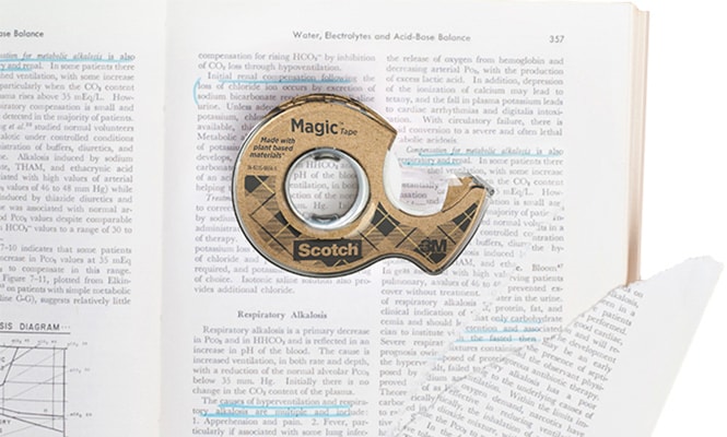 Ruban Scotch® Magic™ 66 % adhésif végétal, sur un livre dont la page est déchirée
