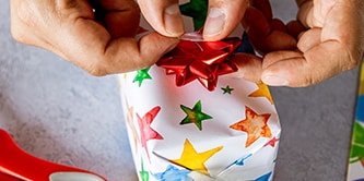 Utilisation de papier d'emballage étoilé et finition du look d'emballage cadeau avec une étoile en ruban sur le dessus
