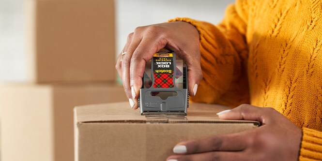 Femme utilisant le ruban d'emballage Scotch Box Lock
