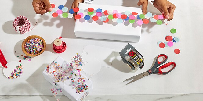 Femme et sa fille emballant une boîte cadeau avec du ruban confetti fabriqué en collant des confettis colorés sur du ruban d'emballage Scotch®

