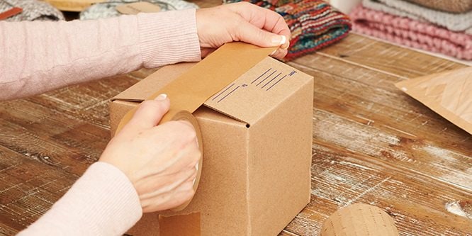 Personne qui emballe un carton à l'aide du ruban d'emballage papier Scotch® Box Lock™
