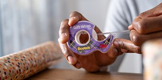 Homme emballant un cadeau avec le ruban Scotch® Spécial Cadeau
