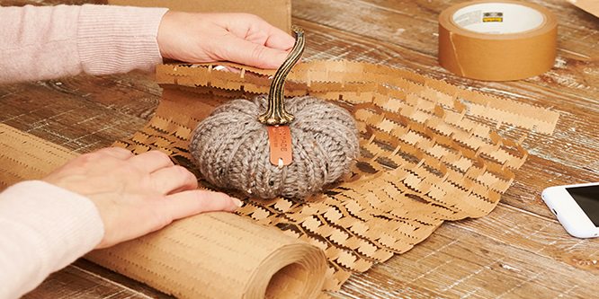 Une personne qui enveloppe un article avec le film de protection Scotch® Box Lock™
