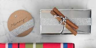 Emballage de Noël épicé créé en utilisant un bâton de cannelle attaché sur le dessus d'un cadeau
