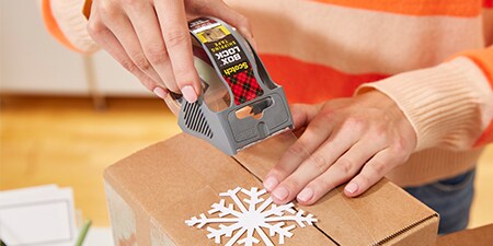 Scellage d'un cadeau de vacances à l'intérieur d'un colis en utilisant le ruban Scotch® Box Lock™ Tape
