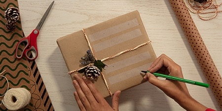 Création d'étiquettes cadeaux en utilisant le ruban Scotch® Magic™ Tape sur un cadeau emballé avec du papier d'emballage simple
